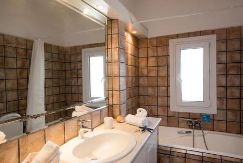 a bathroom with a sink and a mirror and a tub at Villa Waves in Agios Ioannis Mykonos