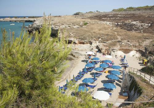 a bunch of umbrellas and chairs on a beach at Corvino Resort in Monopoli