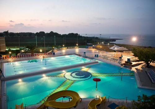 a large swimming pool with blue water at night at Corvino Resort in Monopoli