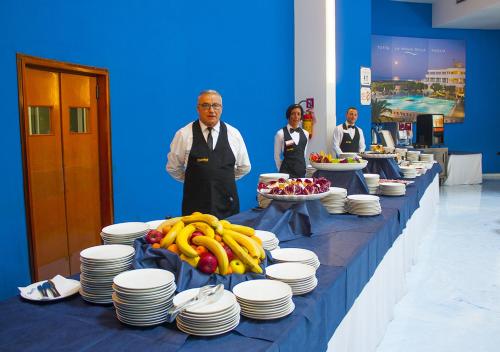 a group of people standing next to a table with plates and fruit at Corvino Resort in Monopoli