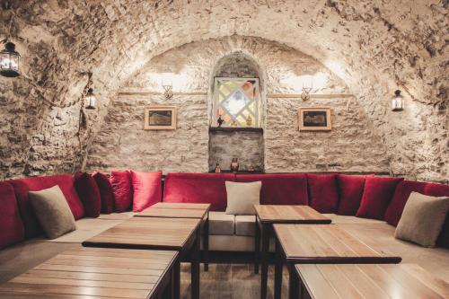 a restaurant with red seats and a stone wall at Hotel Kastro in Gjirokastër