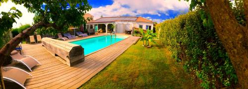 une terrasse en bois avec une piscine et une maison dans l'établissement Villa Felin Feline, à LʼIsle-sur-la-Sorgue