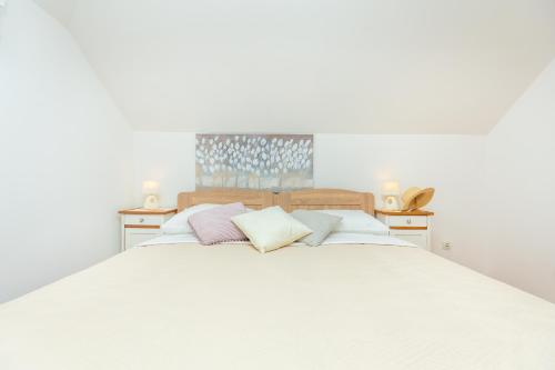 Elle comprend un grand lit blanc avec des draps et des oreillers blancs. dans l'établissement The Loft, à Dubrovnik