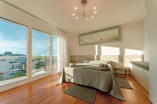 een slaapkamer met een bed en een groot raam bij Soleis Sea View Spa Apartment in Lignano Sabbiadoro