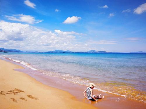 a woman is sitting on the beach at The Mangrovetree Sanya Resort in Sanya