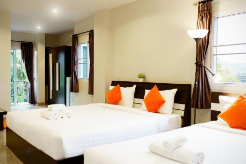 a bedroom with two beds with orange and white pillows at Me Dream Residence in Surat Thani