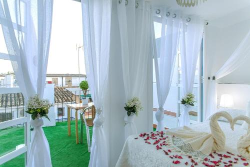 コルドバにあるViviendas Turísticas La Luna Aticoのベッドルーム1室(白いカーテン、バラのベッド付)