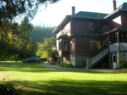 a house with a car parked in front of it at Sasquatch Crossing Eco Lodge B&B in Harrison Mills