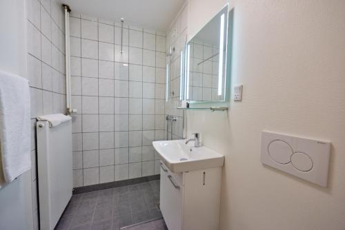 a white bathroom with a sink and a mirror at Danhostel Vitskøl Kloster in Ranum