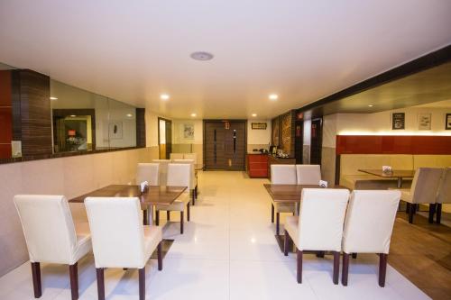 a dining room with white chairs and wooden tables at Hotel Kapilavasthu in Palakkad