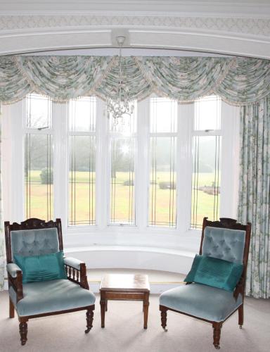 two chairs and a table in front of a window at Petwood Hotel in Woodhall Spa