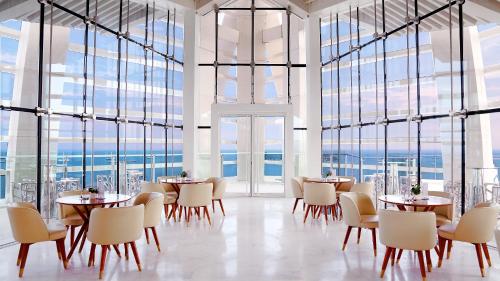 a restaurant with tables and chairs and large windows at The Mangrovetree Sanya Resort in Sanya