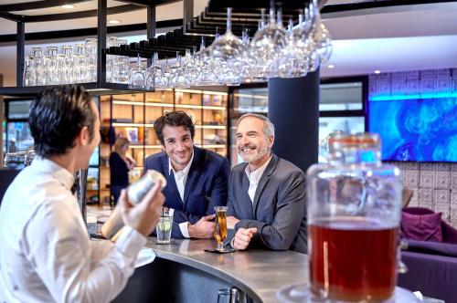 three men sitting at a bar in a restaurant at Campanile PRIME - Nice Airport in Nice