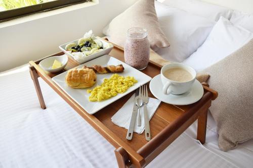 a tray of breakfast foods and a cup of coffee on a bed at Mucura Hotel & Spa in Cartagena de Indias