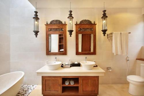uma casa de banho com 2 lavatórios, uma banheira e um WC. em Kamajaya Villas em Ubud