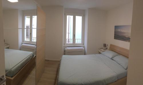 a small bedroom with two beds and two windows at Riva Guest House Apartment in Riva del Garda