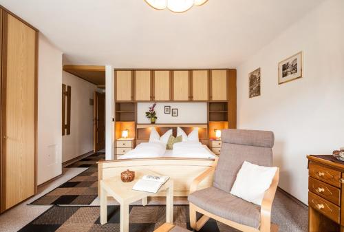 a bedroom with a bed and a chair and a table at Haus Bergesblick in Leutasch