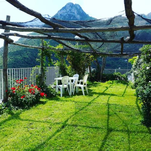a yard with two white chairs and a pergola at Le Terrazze di Cristina in Vietri sul Mare