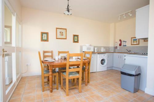 a kitchen with a wooden table and chairs and a sink at Kilkee Holiday Homes Type A by Trident Holiday Homes in Kilkee