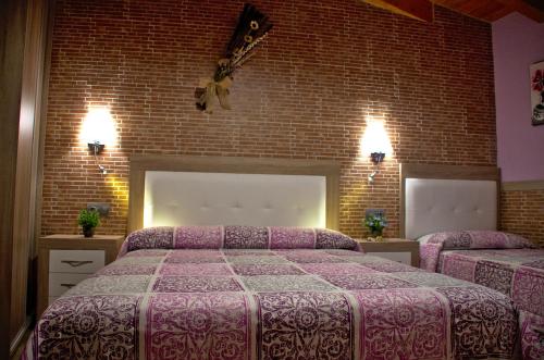a bedroom with two beds and a brick wall at casa oliva la bodegueta in Abiego