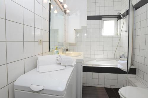 La salle de bains blanche est pourvue d'un lavabo, de toilettes et d'une baignoire. dans l'établissement COLMAR city center place de l'Ancienne Douane - Apartment 