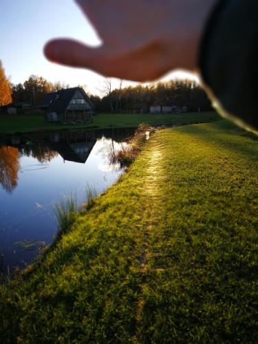 a hand is pointing at a body of water at Sodyba Vieversynė in Duokiškis
