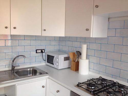 um balcão de cozinha com um lavatório e um micro-ondas em La Casa Blanca y Azul em SantʼAntìoco