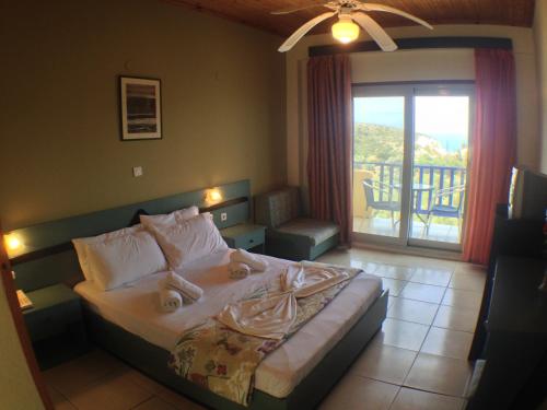 a bedroom with a bed with a view of a balcony at Politia Hotel in Agios Nikitas