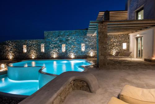 a swimming pool in the backyard of a house at night at Amallini Suites Mykonos in Super Paradise Beach