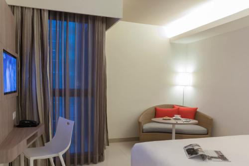 a hotel room with a bed and a chair and a window at Travelodge Pattaya in Pattaya Central