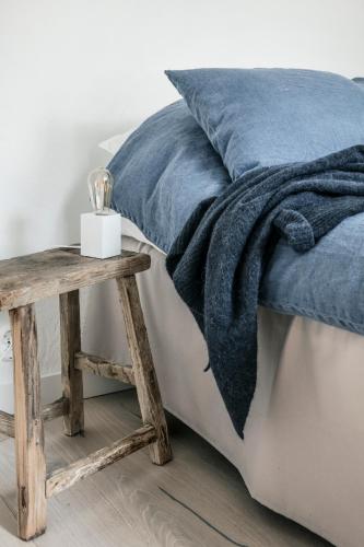a bed with a blue blanket and a wooden table at Siggesta Gård in Värmdö