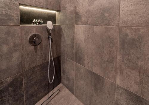 a bathroom with a shower with a phone on the wall at Atelier Hotel in Ljubljana