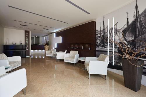 a dining room with white chairs and tables and a painting of ships at Hotel Villa Smeralda in Malcesine