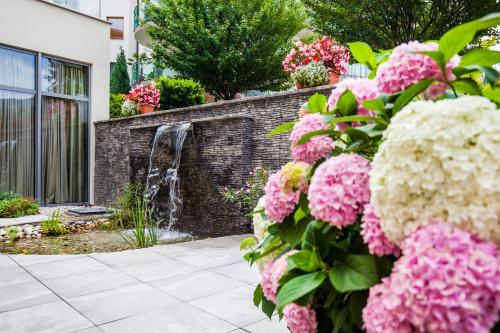 a garden with pink flowers and a waterfall at Wellness Hotel Panorama in Trenčianske Teplice