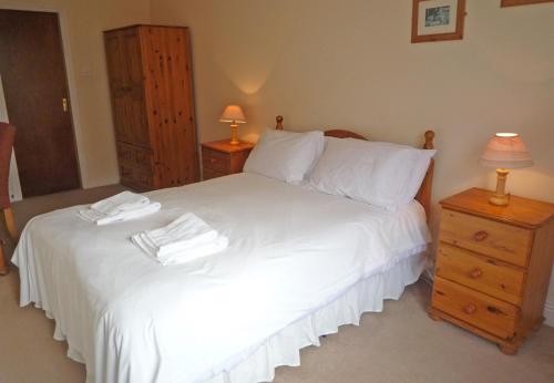 una camera da letto con un letto con lenzuola bianche e due lampade di Kilkee Holiday Homes (GF - Sleeps 5) a Kilkee