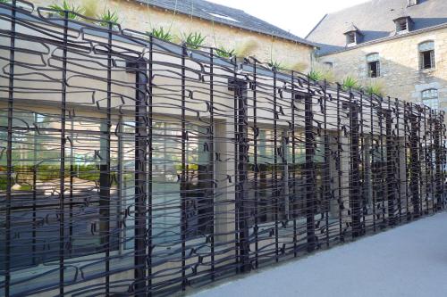 a metal fence with plants on the side of a building at Hôtel Ginkgo - SPA Biloba in Quimper