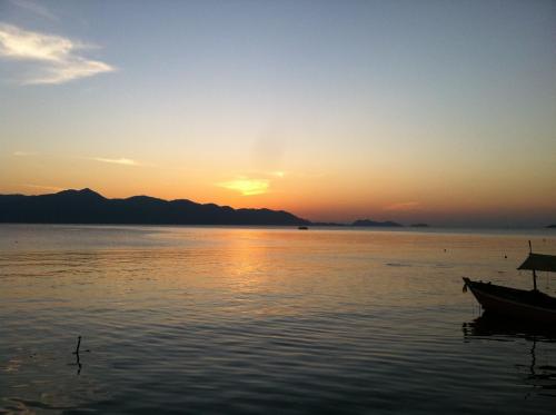 a boat sitting in the water at sunset at Ban Sulada Guest House in Laem Ngop