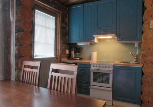 a kitchen with blue cabinets and a stove and chairs at Salmikangas G4 in Ruka