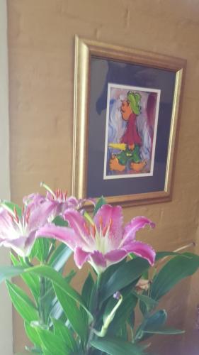 a vase with a flower in front of a picture at African Silhouette Guesthouse in Benoni