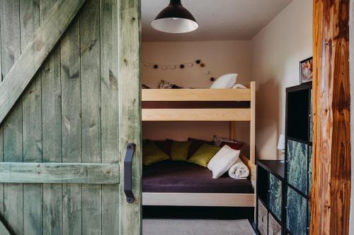 Pokój z 2 łóżkami piętrowymi i ścianą z drewna w obiekcie Jama Jagodna w mieście Spalona