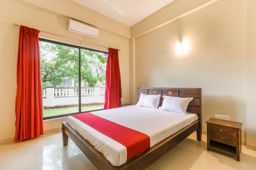 1 dormitorio con 1 cama con cortinas rojas y ventana en StayVista at Greenwoods Villa 8 with Private Pool, Terrace, Lift & Ping-Pong Table, en Lonavala