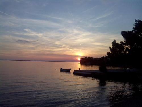 a sunset over a lake with a boat in the water at Apartments Ivanka in Starigrad