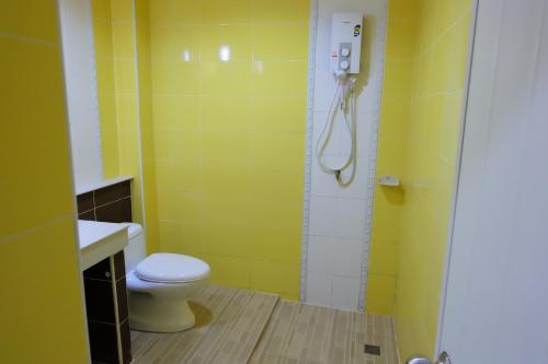 a yellow bathroom with a toilet and a shower at Sakaeogarden Hotel in Sa Kaeo