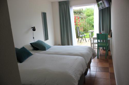 2 Betten in einem Zimmer mit einem Tisch und einem Fenster in der Unterkunft Bluesheep-texel in De Koog