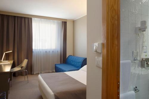 a hotel room with a bed and a blue chair at City Hotel & Suites in Foligno