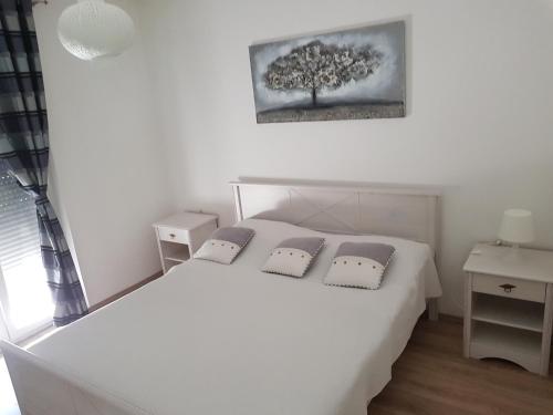una camera con un letto bianco e un albero sul muro di Holiday Home Begonja a Privlaka (Brevilacqua)