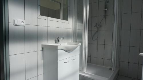 a white bathroom with a sink and a shower at Apartment Hornický dům in Sokolov