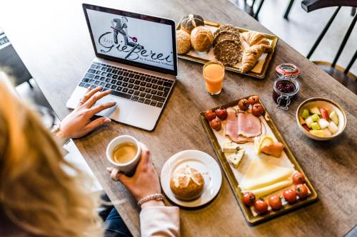 a woman sitting at a table with a laptop and food at Best Western Plus Parkhotel Velbert in Velbert