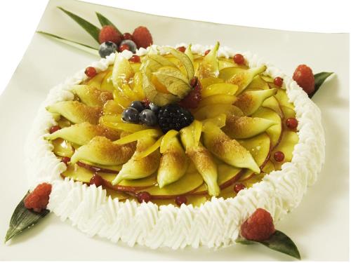 a cake with fruit on top on a table at Hotel Savoy in Pesaro