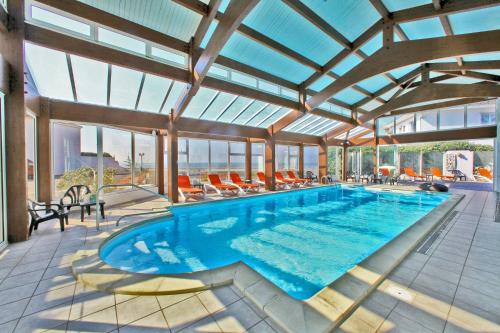 una piscina in una grande stanza con un grande soffitto di vetro di Hotel Les Dunes a La Tranche-sur-Mer